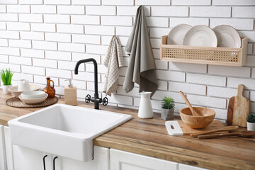 Counters with sink and clean napkins near white brick wall in kitchen