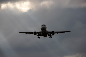 Airplane flying through dramatic clouds with sunlight breaking through, showcasing the beauty of aviation and the thrill of travel in a captivating sky scene
