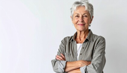 Confident elderly woman in smart casual clothes looking at the camera with arms crossed isolated over white background. 