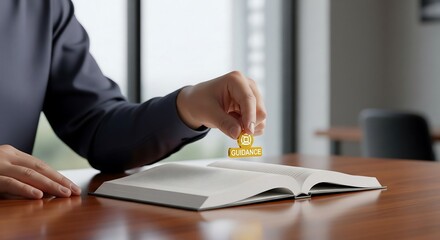 A person stamps a gold seal onto an open book on a wooden desk, indoors.