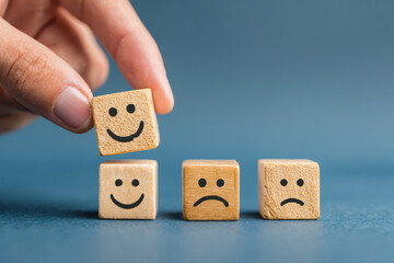 A hand is adding three wooden blocks with smiley faces