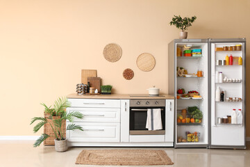 Open big refrigerator with products and white counters near beige wall in interior of kitchen © Pixel-Shot
