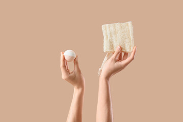 Female hands holding bath bomb and loofah sponge on beige background