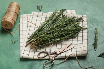 Fresh rosemary with spool of rope and scissors on green grunge background
