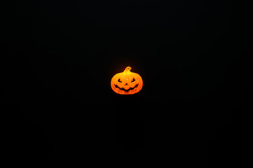 Jack o lantern with orange light puts on black background for Halloween holiday background.