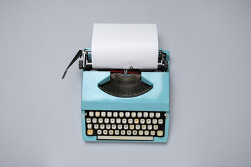 Vintage blue typewriter with blank paper sheet on white background