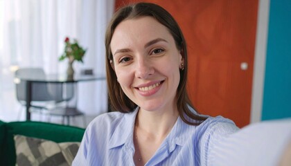 A happy and charming young housewife enjoys well-being sitting on the sofa, taking selfies alone and posing for portraits.