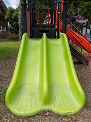 A Vibrant Green Double Slide on a Playground.