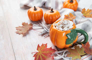 Pumpkin mug of hot chocolate with autumn leaves