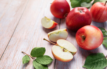 Red apples and slices on light wood background