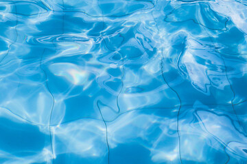 Blue swimming pool water surface and ripple wave background. Sun Reflection in swimming pool.