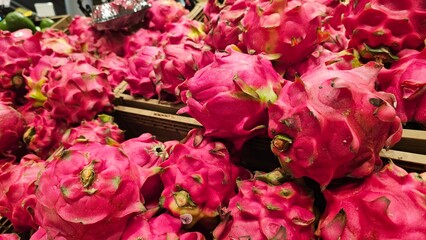 Pile of vibrant pink dragon fruits (pitaya) in a market. Fresh exotic tropical produce, healthy food.