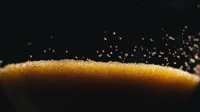 Close-up photograph of golden glittering sand leaking out of an hourglass.