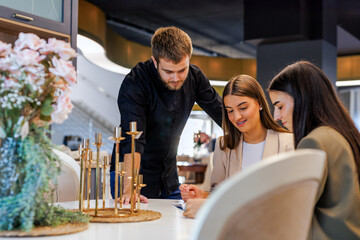 Salesman consulting female customers at furniture showroom