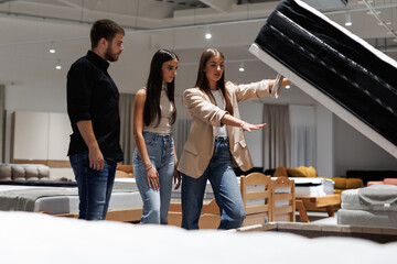 Salesperson showing mattress storage feature to couple