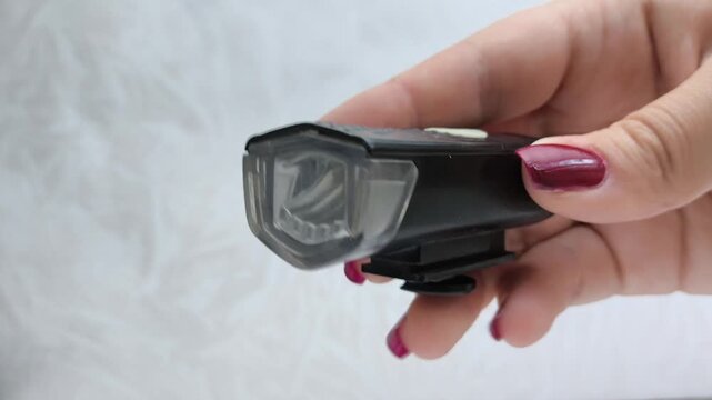 Bicycle flashlight in a woman's hand close-up. A woman turns on and off a bicycle flashlight