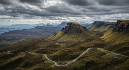 Dramatic mountain landscape with winding road under a moody overcast sky ideal for commercial applications
