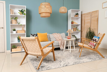 Interior of stylish living room with grey sofa, armchairs and shelf units