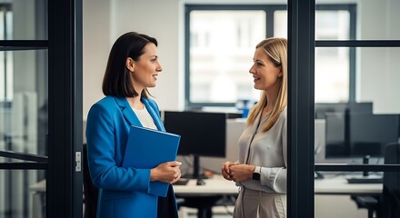Two professional women in an office discussing business matters
