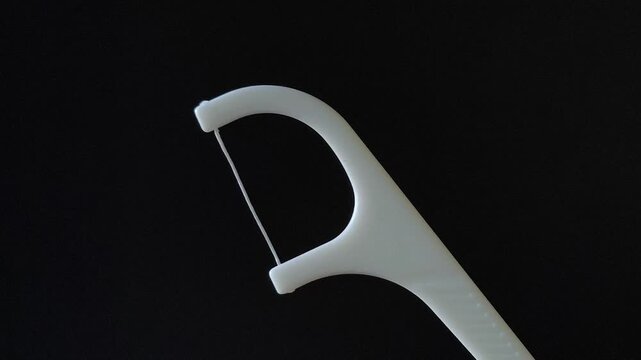 Flosser for teeth in a woman's hand on a black background. Oral hygiene, cleaning of food residues between the teeth