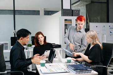 Diverse business team collaborating in a meeting with laptops, tablets, and reports, symbolizing planning, analysis, teamwork, and professional success.