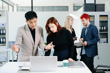 Diverse business team collaborating with laptops, tablets, and reports in a modern office, symbolizing strategy, teamwork, and corporate success.