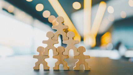 Wooden human figures stacked in pyramid shape symbolizing teamwork, leadership, collaboration, and organizational success, perfect for business, HR, corporate strategy, or team-building content.