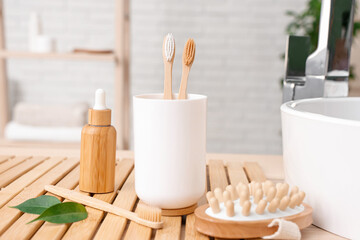 Cup with toothbrushes and toiletry on table in bathroom, closeup
