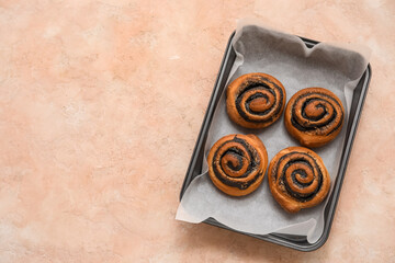 Baking tray with tasty poppy buns on pink grunge background