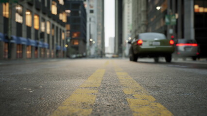 Cars pass through a lively city street under the soft morning light, revealing towering buildings and a peaceful road. The scene captures the essence of urban life at dawn.