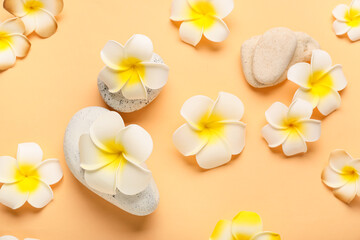 Pebble stones with beautiful plumeria flowers on orange background