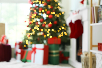 Blurred view of living room with glowing Christmas tree, presents and fireplace