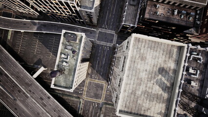 This aerial view reveals a bustling urban scene with intersecting streets and tall buildings. The sunlight casts shadows across the rooftops, highlighting the citys architecture and layout.