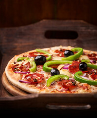 Pizza with chorizo ​​sausage, mozzarella cheese, green pepper and black olives. Rustic wooden background. Soft focus.	