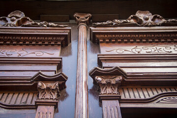 Obraz premium Close-up of handcrafted colonial wooden doors in Puebla, Mexico, showcasing artisanal Baroque details in rich mahogany and copper tones.