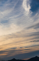 Layered Evening Clouds Above Dark Mountain Silhouettes