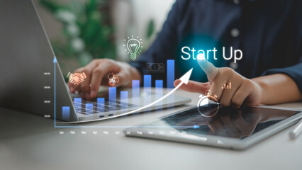 Startup business growth concept showing hand pointing to graph on virtual screen, with rising bar chart, innovation icons, and technology interface, symbolizing success and entrepreneurship.