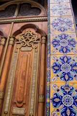 Vibrant Talavera arch frames a richly carved wooden door with brass studs and floral leaded glass in Puebla, Mexico, a true jewel of Mexican artisan craftsmanship.