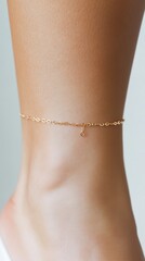 Minimalist gold chain anklet on caucasian female foot against soft background