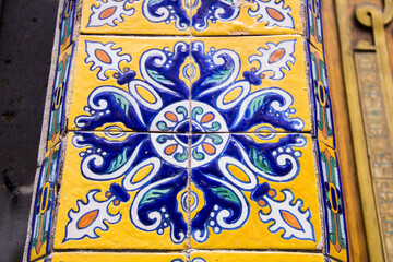 Macro close-up of a single Talavera tile in Puebla, Mexico, showcasing intricate floral patterns, vibrant colors, and artisanal craftsmanship.