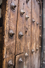 Timeworn Mexican Baroque door marked by iron studs and deep wood scars, capturing centuries of colonial craftsmanship, material strength, and architectural memory.