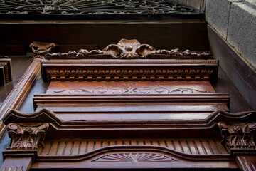 Colonial Baroque fronton and lunette above a doorway, featuring hand-carved floral ornamentation and an ornate wrought iron grille in Puebla, Mexico.
