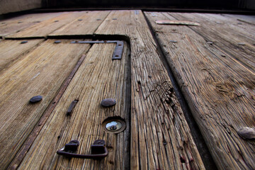 Low-angle view of a weathered wooden door in Puebla, Mexico, revealing aged planks, forged iron...