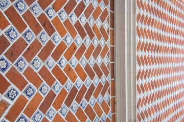 Close-up of red brick wall with talavera tile accents, showcasing intricate texture and colonial Mexican craftsmanship.