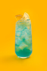 Blue cocktail in a glass on a yellow background.
