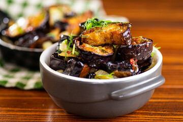 Fried eggplants with onions and dill in a frying pan