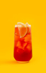 Red cocktail in a glass on a yellow background.