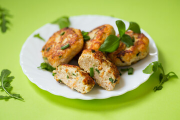 Homemade chicken mince cutlets on a plate isolated on green background