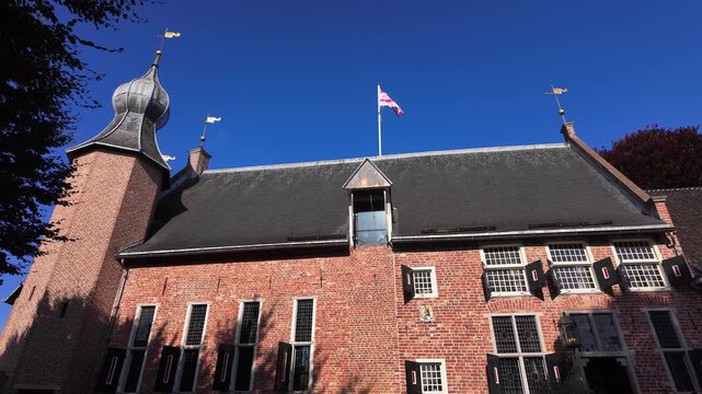 Detailed view of a historic brick castle tower with weather vanes and Drenthe flag under bright blue sky in Coevorden, Drenthe, Netherlands | Coevorden, Drenthe, Nederland