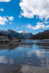 Clear Lech River reflecting snowy mountains and clouds near Füssen, Bavaria, Germany – tranquil alpine landscape with blue sky and crystal water